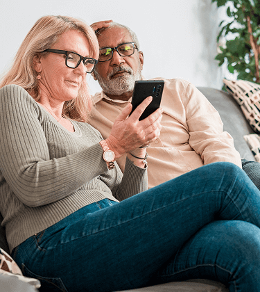 Actor portrayal of an elderly couple looking at a phone together